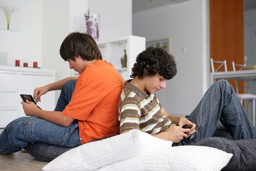 garçons souriants assis dos à dos avec une console portable