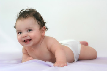 Bébé souriant à plat ventre sur le lit