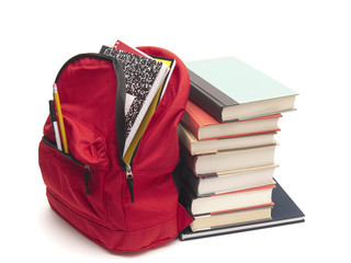 School backpack beside stack of books on white background