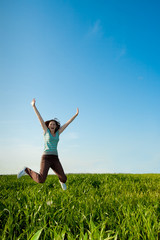 young woman jumping on geen field
