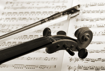 detail von violine und bogen vor notenblättern, sepia