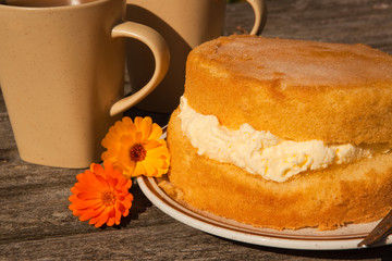 Homemade sponge cake with coffee mugs and marigolds