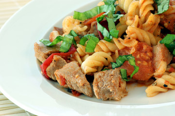 Pasta with baked tomato, meat and basil