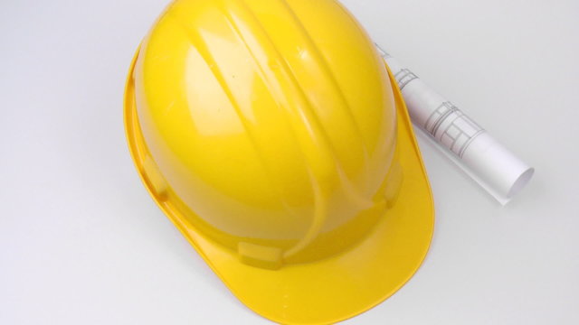High view of a yellow hard hat and a plan turning