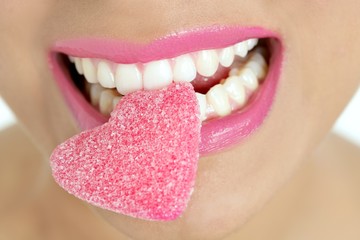 Fototapeta premium Heart shape candy on woman macro mouth