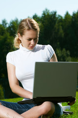 The girl with laptop on a green lawn