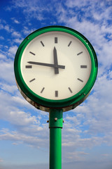 Fototapeta na wymiar green street clock against sky