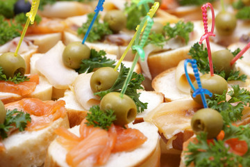 Open sandwiches with red and white fish, olives and greens