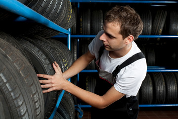 Young mechanic choosing tire in car service