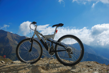 single mountain bike on a mountain rocky peak - obrazy, fototapety, plakaty