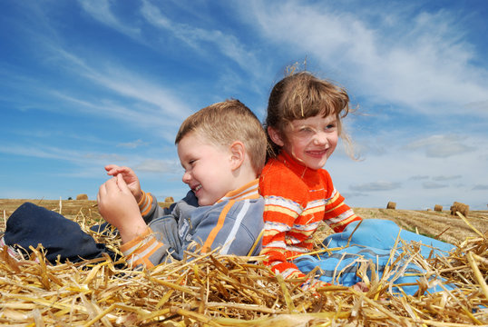 smiling boy and girl in straw outdoors