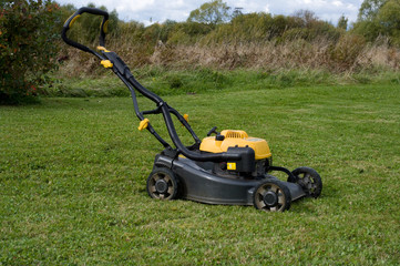 Fototapeta na wymiar Yellow lawn mower on the green field.