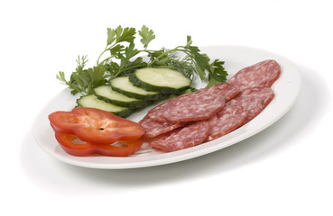 Cut green-stuffs and pieces of sausage on a white dish