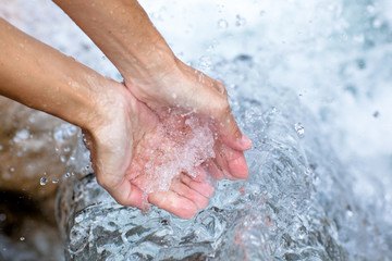 washing hands under clear mountain stream water