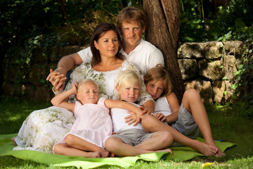 Fototapeta premium parents with three children sitting on blanket