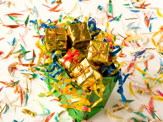 Bag full of small golden gifts around confetti. Shallow DOF.