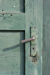 old green painted wooden door and a rusty doorknob