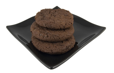 three chocolate cookies on black plate isolated on white