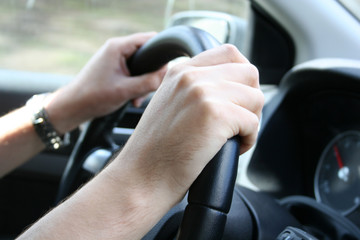 Driver man holds a steering wheel of  his car