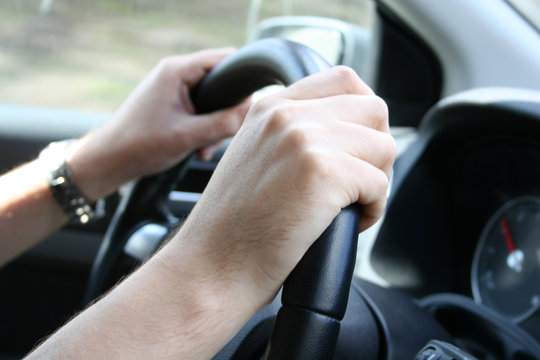 Driver man holds a steering wheel of  his car