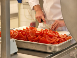 Professioneller Koch schneidet und entkernt viele Tomaten als Kochvorbereitung