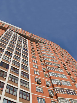 one urban high building, red brown brick, blue sky