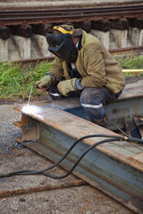 The worker- welder in a protective mask welds metal
