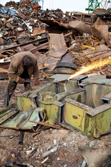 Welder using an acetylene torch to cut through a metal
