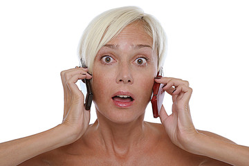 Mujer escuchando a traves de dos telefonos moviles