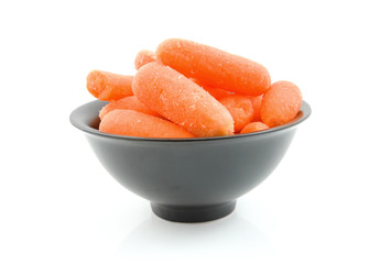 fresh raw carrots in black bowl over white background