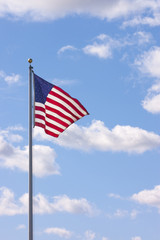 Us Flag waving in the breeze with cumulus clouds in the sky