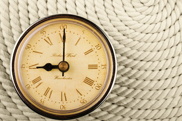 Clock with Roman numerals on cord background. 9