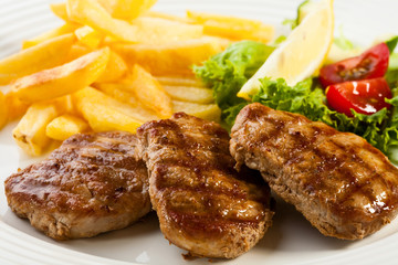 Grilled steaks, fries and  vegetable salad