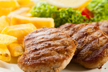 Grilled steaks, fries and vegetable salad