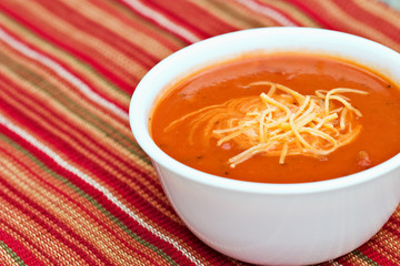 Tomato soup garnished with cream and cheddar cheese.