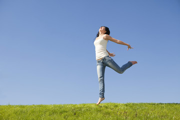 pretty young woman jumping on green grass