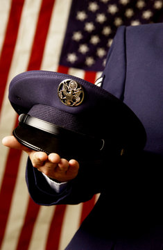 Military Personnel Holding Hat