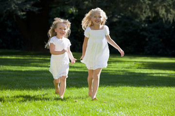 Two Pretty Young Girls Running Through A Sunlit Green Park