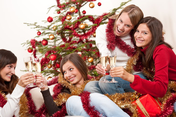 Four smiling women with glass of champagne on Christmas