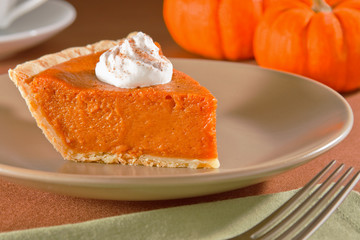 Slice of freshly cut pumpkin pie with whipped cream