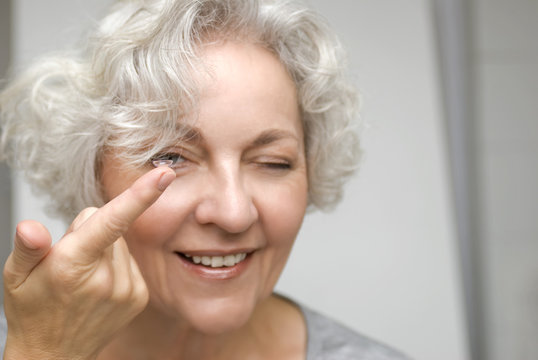 ältere Frau begutachtet genauer eine Kontaktlinse