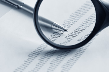 Magnifying glass  and pen over financial report