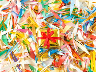 Small golden gift on the colored confetti. Shallow DOF.