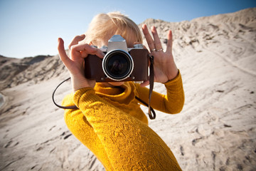 woman with a old camera taking photos in the desert