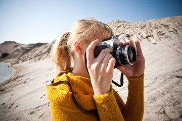 woman with a old camera taking photos in the desert
