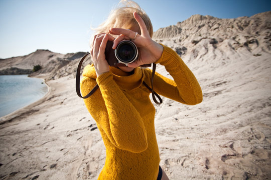 woman with a old camera taking photos in the desert
