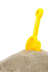 Sand pile with yellow toy shovel over white background