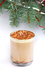 mug of capuccino under fir-tree branch