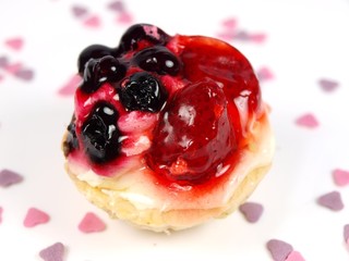 Delicious fruit cake with sweet hearts on white background
