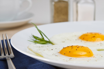 Two fried eggs with cracked black pepper and  tarragon